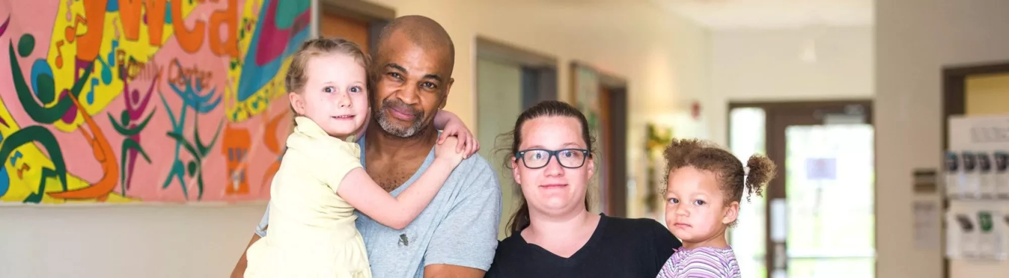 Family of four with 2 young girls held by their parents